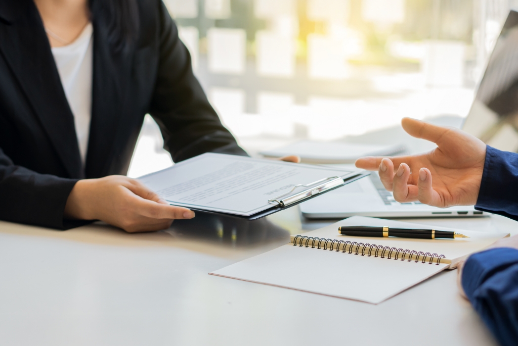 A Professional Person Holding a Document While the Other is Pointing at it.
