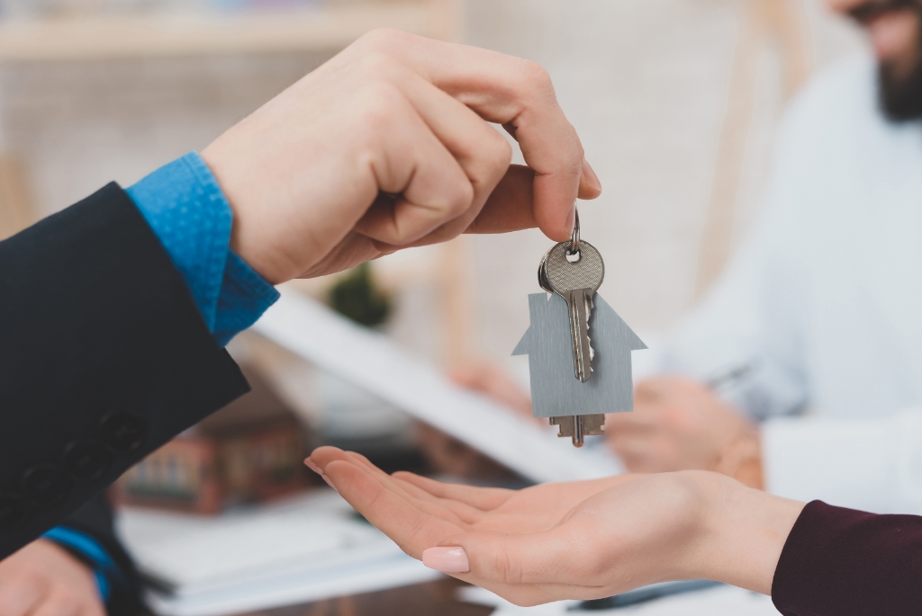 A Professional Person Handing Over a Key to Another Person.