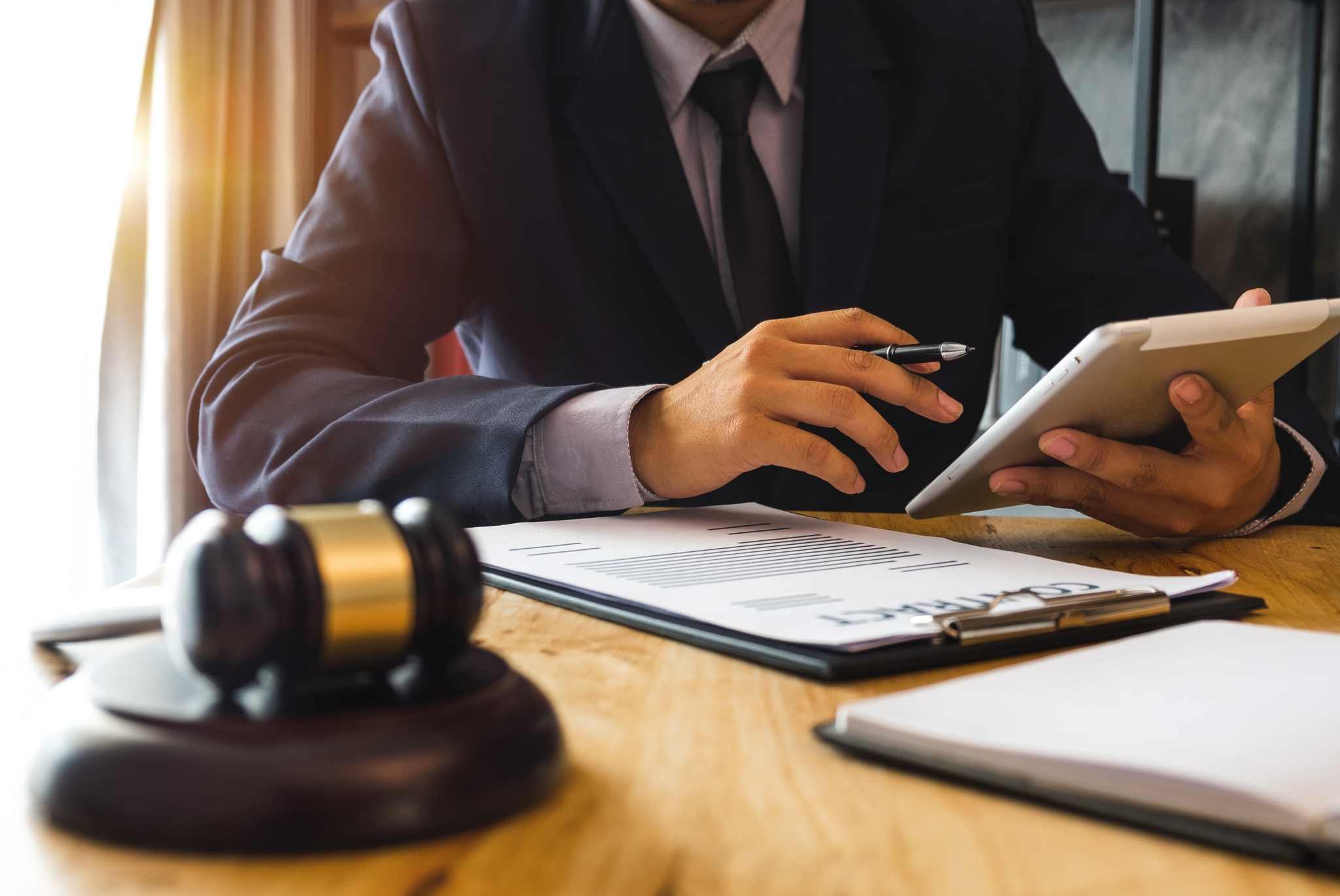 Law Professional Carefully Examining Contract Files Holding a Tablet